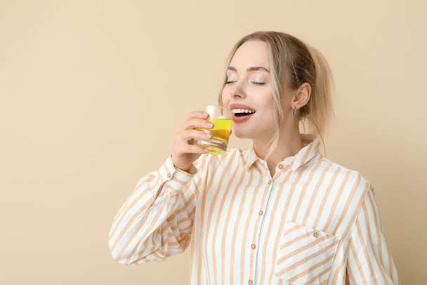 Nuori nainen, jolla on liuennut tabletti lasillisessa vettä beige taustalla - Valokuva, kuva