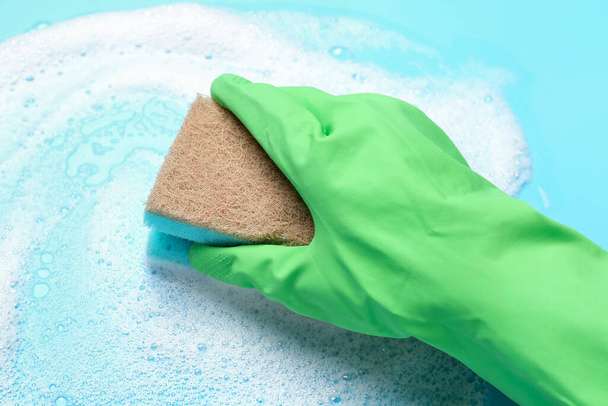 Woman with sponge and foam on blue background, closeup - Photo, image