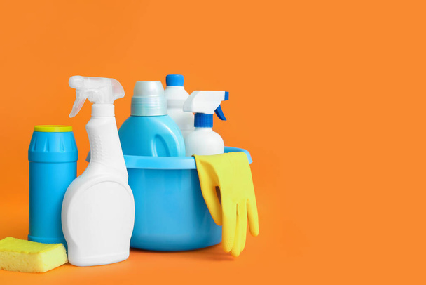 Bowl with different cleaning supplies on orange background - 写真・画像