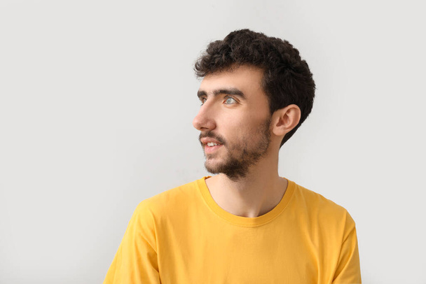 Junger brünetter Mann mit stilvoller Frisur auf hellem Hintergrund, Nahaufnahme - Foto, Bild