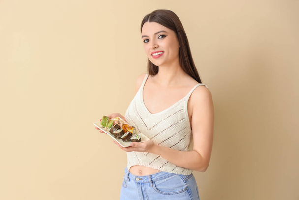 Young woman with sushi on beige background - Foto, Imagem