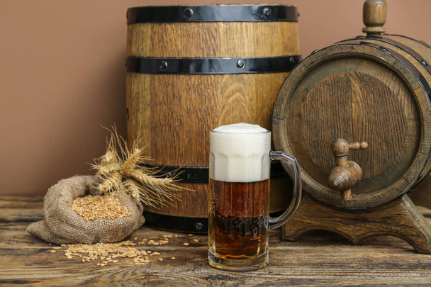 Mug of cold beer and wooden barrels on table. Oktoberfest celebration - Zdjęcie, obraz