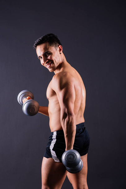 Shirtless bodybuilder showing his great body and holding dumbells. - Fotoğraf, Görsel