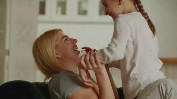 Young positive mom having fun with her daughter. The family on the couch will have fun together. High quality 4k footage - Footage, Video