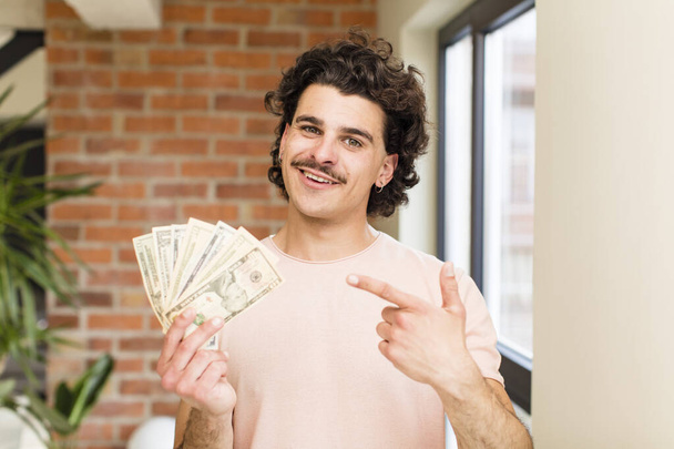 young handsome man with dollar banknotes at home interior - Photo, Image