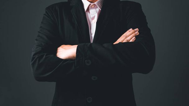 Un hombre de negocios con un traje negro está de pie entre los brazos, expresando confianza y éxito. - Foto, Imagen