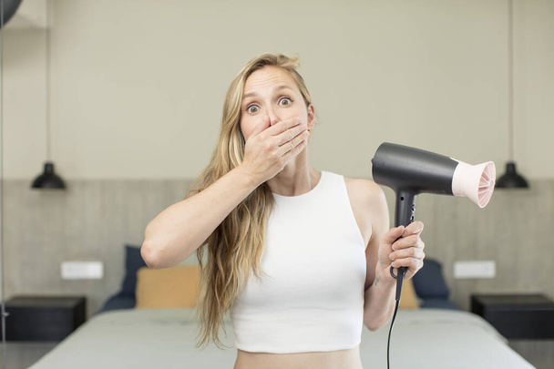 covering mouth with a hand and shocked or surprised expression. hair dryer concept - Фото, изображение