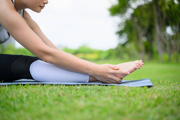 Healthy young woman enjoying and relaxing yoga outdoor in green park, Woman doing yoga exercise outdoor with happiness, Positive fit woman practicing yoga on open air outside in morning - Фото, зображення