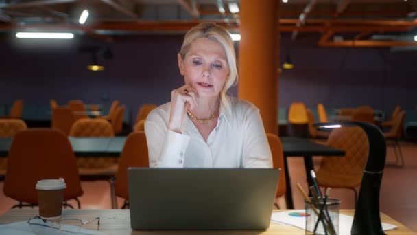Dojrzała amerykańska biznesmenka po 50-tce komunikująca się przez wideo rozmowę. CEO businesswoman mówi patrząc na laptopa, online konferencji odległość biuro czat, wirtualne szkolenia, ludzie technologii - Materiał filmowy, wideo