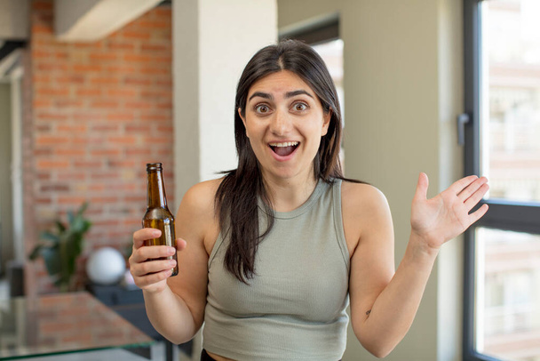 young woman feeling happy and astonished at something unbelievable. beer bottle - Zdjęcie, obraz