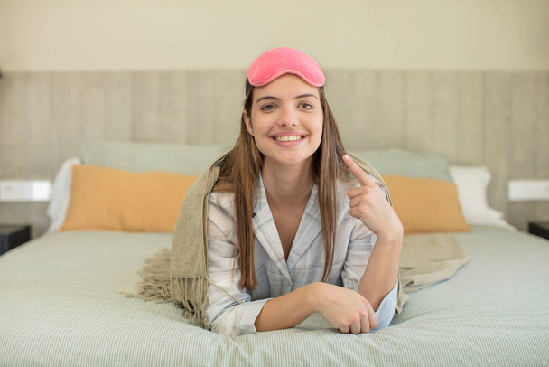 young pretty woman smiling cheerfully, feeling happy and showing a concept. nightwear concept - Foto, Imagen