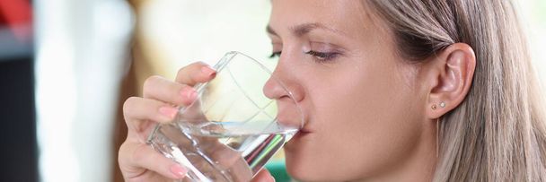 Şeffaf bardaktan su içen susamış kadının portresi. Su dengesi ve sağlık hizmeti kavramı - Fotoğraf, Görsel