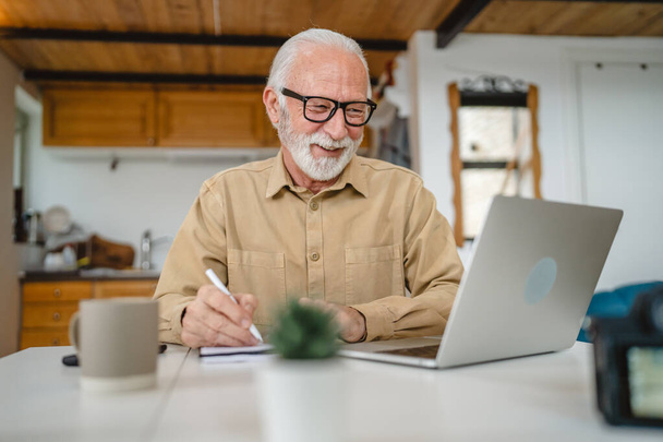 One senior caucasian man grandfather with beard and eyeglasses work on laptop use computer at home online happy smile success - Photo, Image