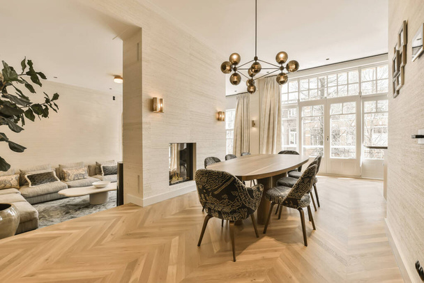 una sala da pranzo con pavimenti in legno e pareti in mattoni bianchi in camera è circondata da un camino - Foto, immagini