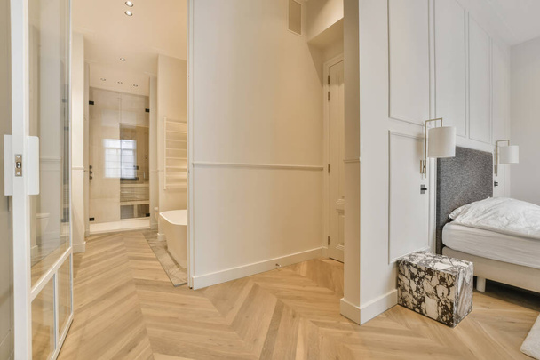 un dormitorio con paredes blancas y suelos de madera en el centro de la habitación, hay un gran espejo en la pared - Foto, Imagen