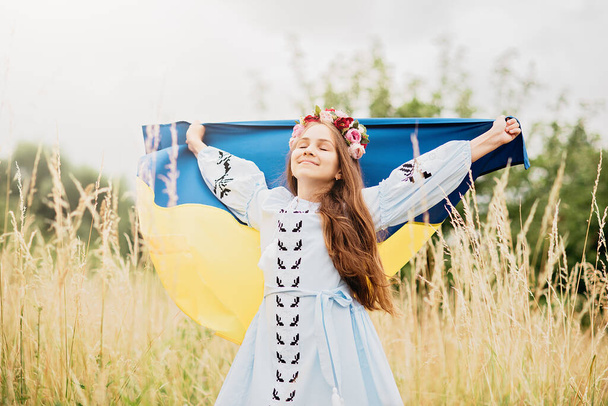 Ukraines Independence Flag Day. Constitution day. Ukrainian child girl in embroidered shirt vyshyvanka with yellow and blue flag of Ukraine in field. flag symbols of Ukraine. Kyiv, Kiev day - Фото, изображение