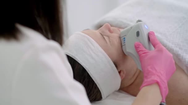 Egy kozmetikai központban professzionális felszereléssel, SMAS ultrahangos arcfelvarró masszázst adunk egy nyugodt női ügyfélnek..  - Felvétel, videó