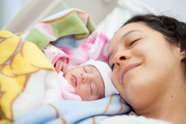 Newborn girl with her mom in the hospital on the day of her birth. Motherhood concept - Photo, Image