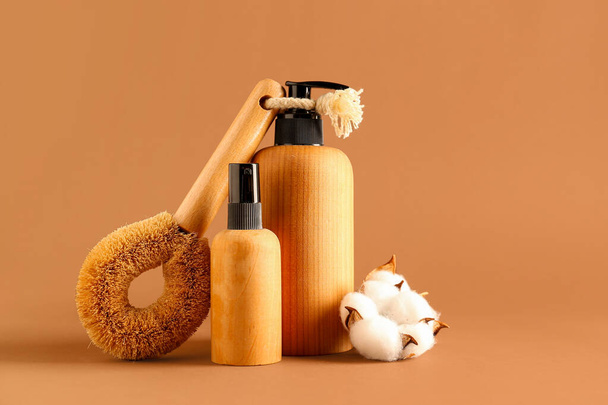 Bottles of cosmetic products, massage brush and cotton flowers on color background - Photo, Image