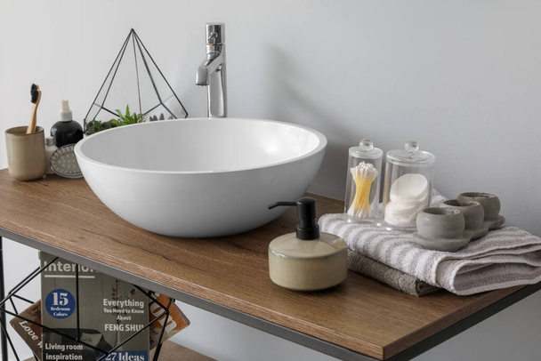 Стол с раковиной, мыльницей и банными принадлежностями в ванной комнате - Фото, изображение