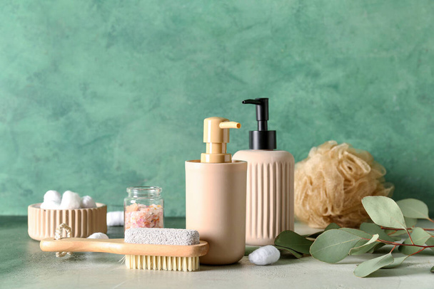 Botellas de productos cosméticos, cepillo de masaje, esponja, bolas de algodón y sal marina sobre fondo de color - Foto, imagen