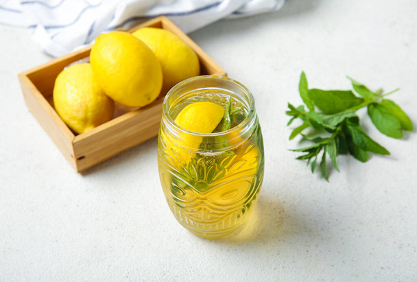 Glass of ice tea and wooden box with lemons on white background - Photo, Image