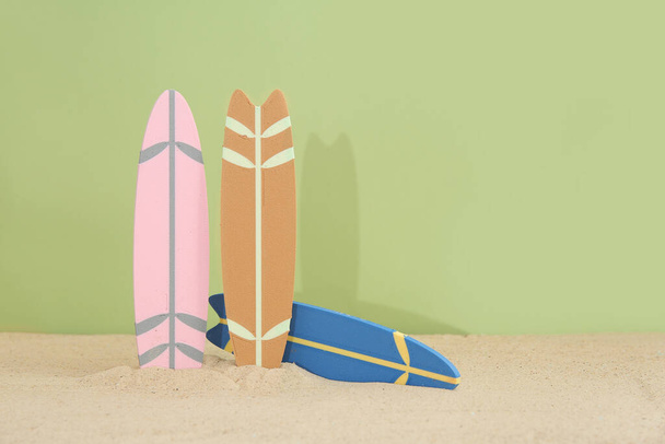 オリーブを背景に砂の上に異なるカラフルなミニサーフボード - 写真・画像