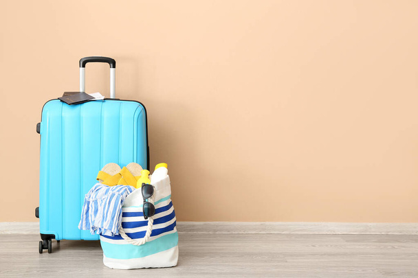 Suitcase with passports, tickets and beach accessories near orange wall. Travel concept - Foto, Imagen