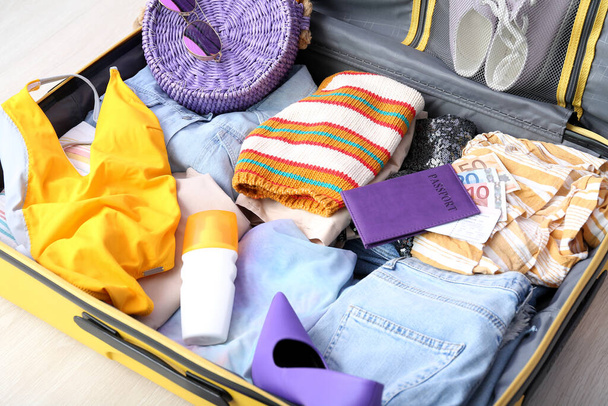 Koffer mit Kleidung, Strand-Accessoires, Reisepass und Ticket auf dem Boden. Reisekonzept - Foto, Bild