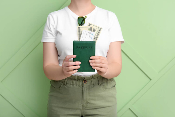 Young woman with passport, ticket and money near green wall. Travel concept - Foto, Imagem