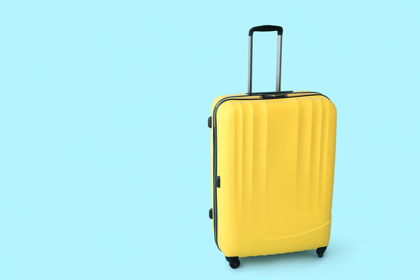 Yellow suitcase on blue background. Travel concept - Фото, изображение