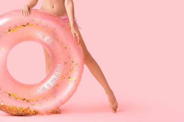 Young beautiful woman in swimsuit with inflatable ring on pink background. Travel concept - Photo, image