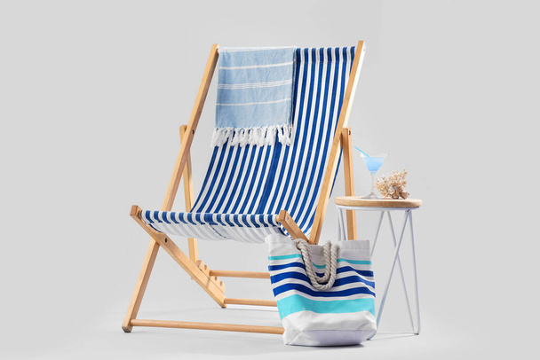 Deckchair with beach accessories, cocktail and coral on stool against grey background - Photo, Image