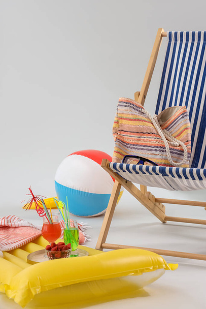 Deckchair with beach accessories, cocktails and bowl of strawberry on grey background. Travel concept - Photo, Image