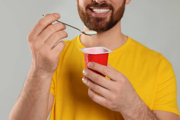 Mann mit köstlichem Joghurt auf hellgrauem Hintergrund, Nahaufnahme - Foto, Bild