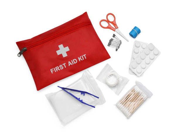 Red first aid kit, scissors, pins, cotton buds, pills, plastic forceps, adhesive plaster and elastic bandage isolated on white, top view - Фото, зображення
