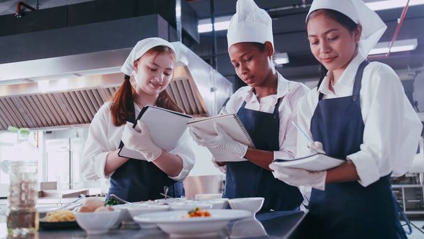 Egy csapat iskoláslány, akik jól érzik magukat, miközben főzni tanulnak. Női diákok főzőtanfolyamon. - Fotó, kép