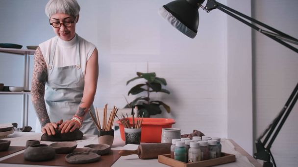 Asiática anciana disfrutando de trabajo de cerámica en casa. Una ceramista femenina está haciendo nueva cerámica en un estudio. - Foto, imagen