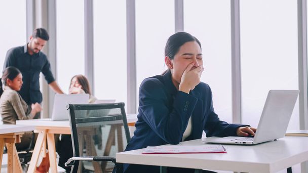 A young company employee is feeling tired while sitting at work for a long time. - 写真・画像
