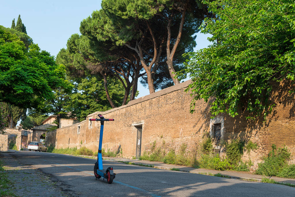 Carretera verde en la antigua ciudad histórica de Roma con pinos y scooter electrónico - Foto, imagen