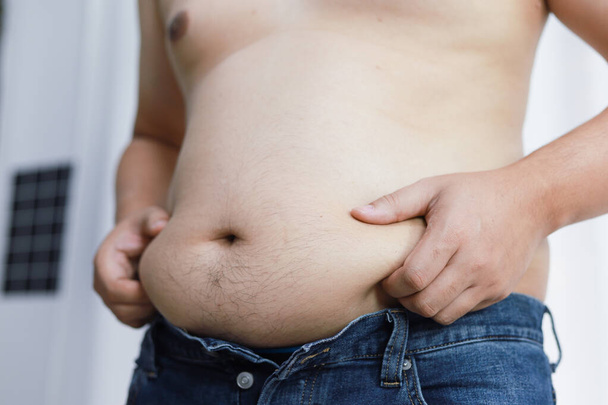 Hombre con vientre gordo en concepto de dieta. Hombre con sobrepeso tocando su vientre gordo y quiere perder peso - Foto, imagen