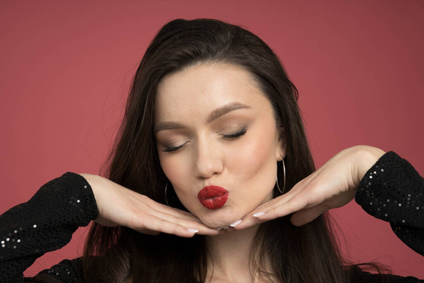 A kiss of a pretty brunette on a red background - Foto, Imagem