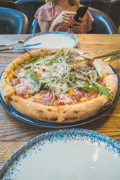 Gustosa pizza italiana con parmigiano, rucola e marmellata sul tavolo in legno del ristorante. - Foto, immagini