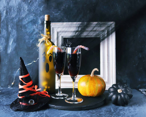Halloween, vino tinto en copas y una botella, calabazas, decoraciones místicas, sobre un fondo negro con telarañas, el concepto de la atmósfera de una fiesta, vacaciones - Foto, imagen