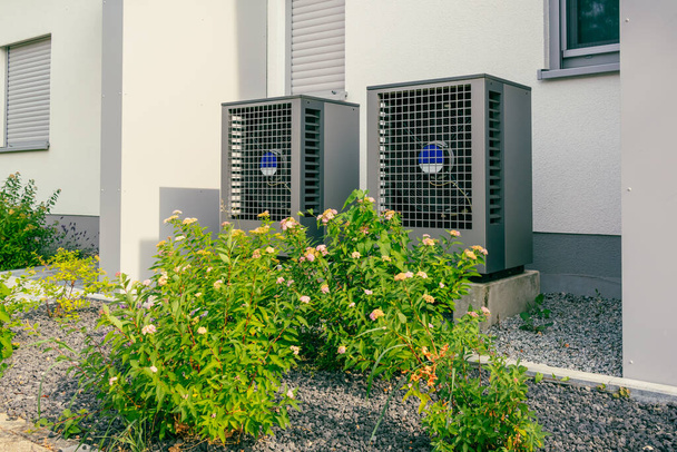 Σύγχρονη αντλία θερμότητας πηγή αέρα εγκατασταθεί έξω από το νέο και σύγχρονο σπίτι της πόλης, πράσινη ανανεώσιμη ενέργεια έννοια της αντλίας θερμότητας - Φωτογραφία, εικόνα