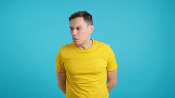 Βίντεο στο στούντιο με μπλε φόντο ενός άνδρα ντρέπεται που η μασχάλη του μυρίζει - Πλάνα, βίντεο