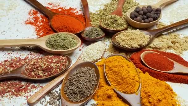Μπαχαρικά φόντο. Ινδικά και ασιατικά μπαχαρικά τροφίμων σε κουτάλια και σκούρο φόντο. Κάρυ, πιπέρι, τσίλι ως συστατικά της ινδικής κουζίνας - Πλάνα, βίντεο