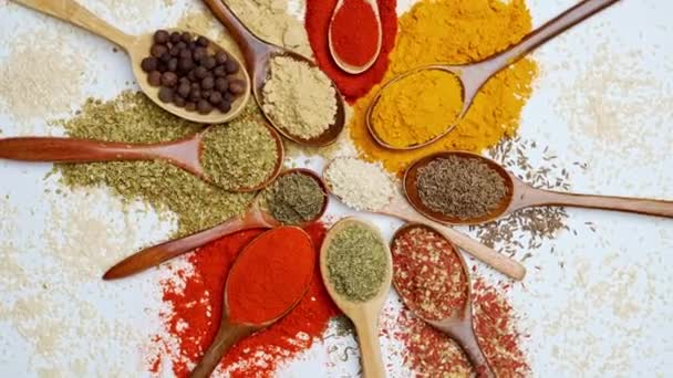 Spezie di sfondo. Spezie alimentari indiane e asiatiche su cucchiai e sfondo scuro. Curry, pepe, peperoncino come ingredienti della cucina indiana - Filmati, video