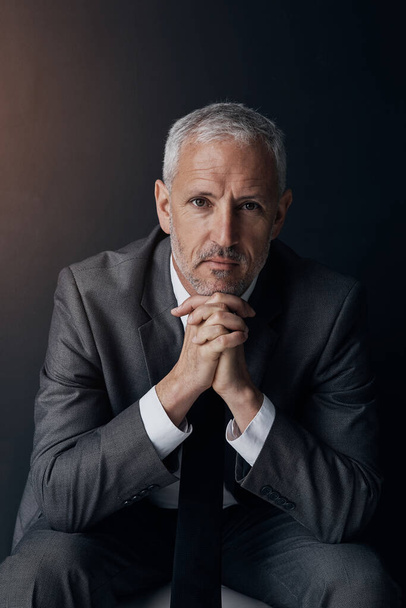 Boss, chair and serious portrait of lawyer, attorney or businessman with ceo on dark background in studio. Confidence, pride and legal business owner, proud senior executive director at law firm - Фото, зображення