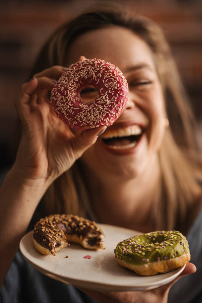 Young happy woman posing with donuts in the cafe. - Photo, image